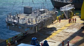 The second deck level of the mine countermeasures ship USS Guardian is guided onto the U.S. Navy contracted vessel M/V Jascon 25.