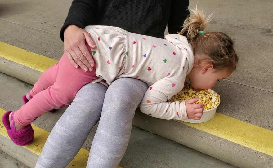 Sarah Alemany's daughter Valentina eats popcorn from Alemany's lap, Dec. 12, 2022.