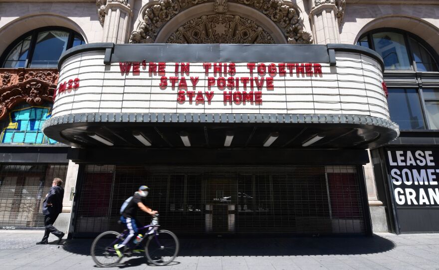 A cyclist in a face mask rides past the Million Dollar Theater in downtown Los Angeles on Monday. Gov. Gavin Newsom announced that California — amid encouraging coronavirus benchmarks — will allow some retail businesses to reopen with modifications as early as Friday.
