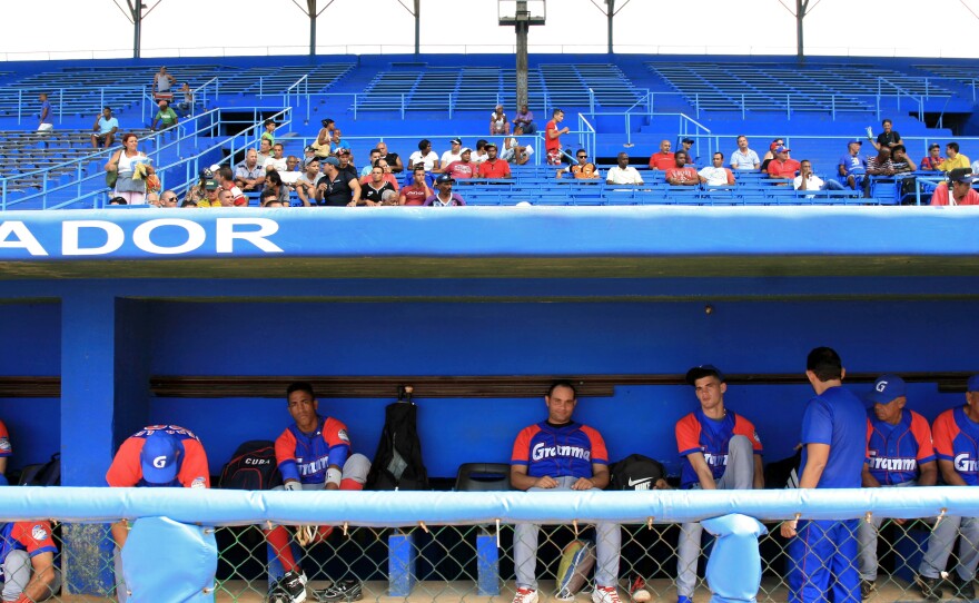 Players for the Alazanes de Granma sit in the dugout at Latin American Stadium.