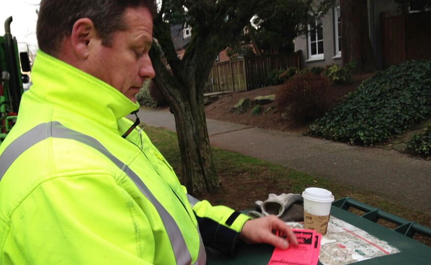 Recology CleanScapes driver Rodney Watkins issues a red tag — the scarlet letter of food waste in Seattle.