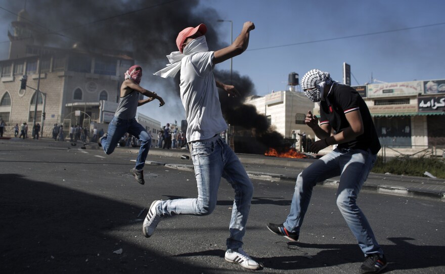 Palestinian protestors throw stones toward Israeli police during clashes in the Shuafat neighborhood in Israeli-annexed Arab East Jerusalem Wednesday, after a Palestinian teenager was apparently abducted in an apparent act of revenge for the murder by militants of three Israeli youths.