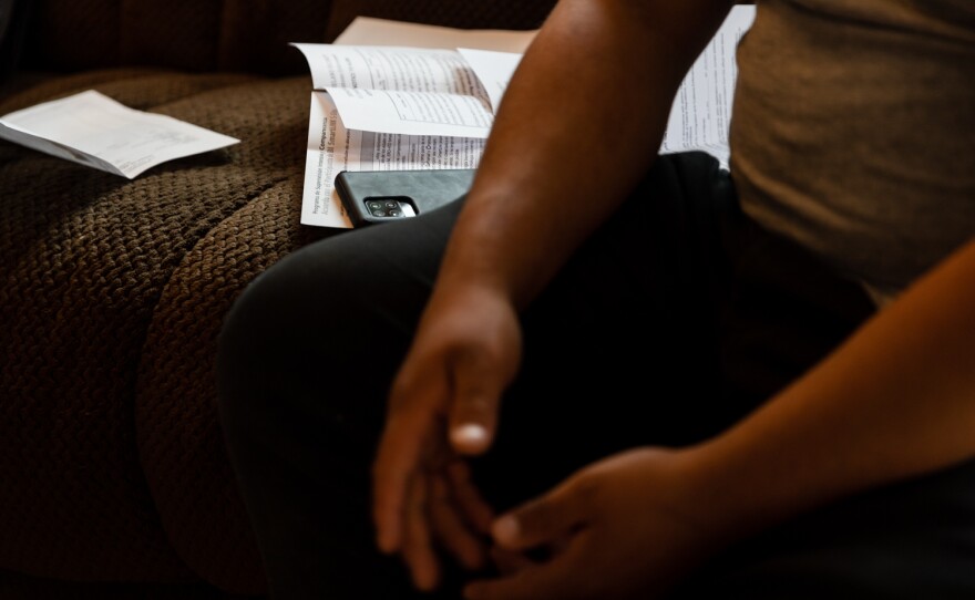 Court papers and a phone device installed with a SmartLINK application sits on an unidentified interviewee’s couch at his home in San Diego on May 19, 2022. The application requires him to check in every Thursday.