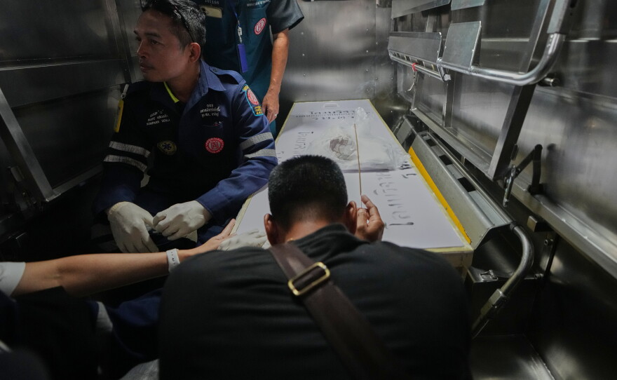 A relative of a victim in a music bar fire pays respect to the victim's body at a police hospital in Bangkok, Thailand, Tuesday, July 14, 2026.
