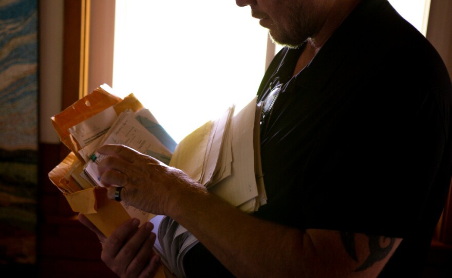 Andrew Simmons flips through paperwork on Jan. 30, 2020, regarding his six children, including his son whose stays in juvenile justice have cost Simmons and his wife nearly $14,000