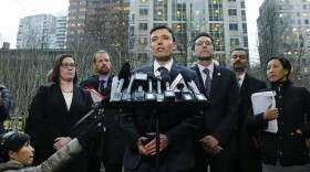 Washington state Solicitor General Noah Purcell, center, talks to reporters as Attorney General Bob Ferguson, third from right, looks on following a hearing in federal court in Seattle, Feb. 3, 2017.