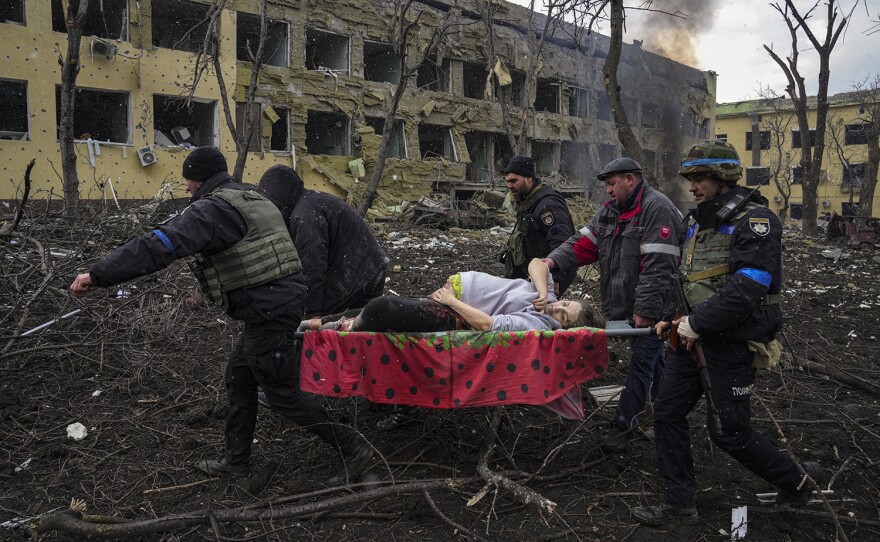 Ukrainian emergency workers and volunteers carry an injured pregnant woman from a maternity hospital damaged by an airstrike in Mariupol, Ukraine, March 9, 2022. The woman was taken to another hospital but did not survive. Still from FRONTLINE PBS and AP’s feature film “20 Days in Mariupol.”