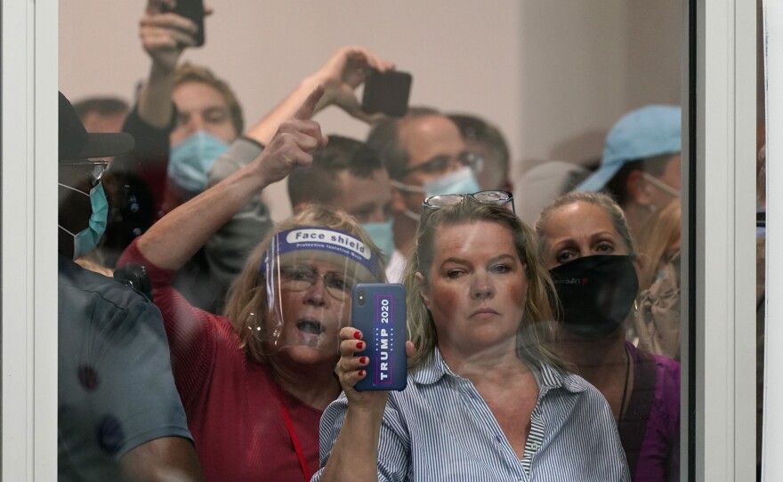 People wanting to be election challengers yell as they look through the windows of the central counting board as police were helping to keep additional challengers from entering due to overcrowding, Wednesday, Nov. 4, 2020, in Detroit. 