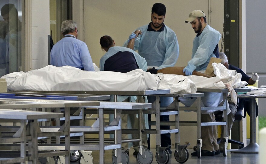 Personnel examine a body at the medical examiner's office on Sunday in Orlando, Fla. A gunman opened fire inside a crowded gay nightclub early Sunday, before dying in a gunfight with SWAT officers, police said.