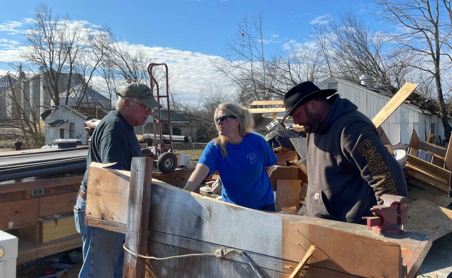 Howard Smith, left, combs through what's left of his workshop in Mayfield with family and friends.