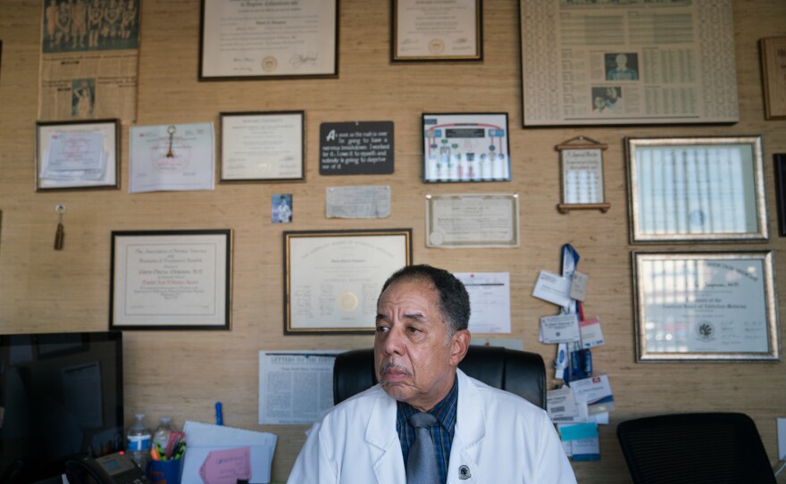 Dr. Chapman in his office at the end of the day on Friday. He waits for the last patient to come in, not wanting them to have to spend the weekend without medication. The walls are covered with awards, certificates, newspaper clippings and family photos.