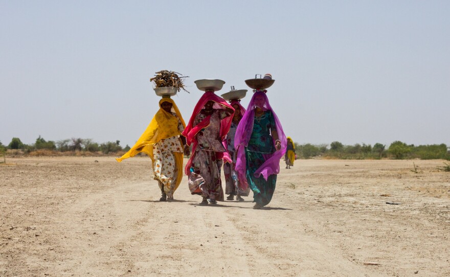Women carry firewood and other supplies into the village.