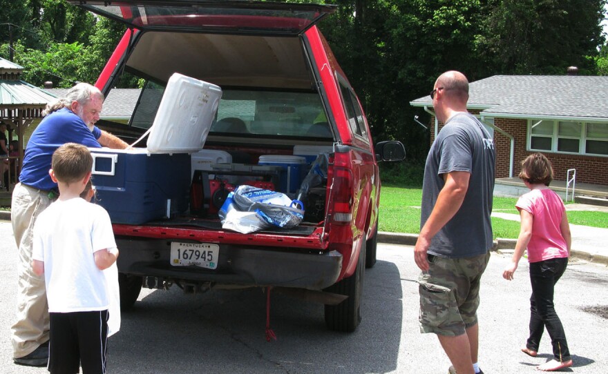 Volunteer Steve Boyd (left) distributes lunches to children from a YMCA truck with the help of YMCA employee Sean Summers (second from right) in Hopkins County, Ky.