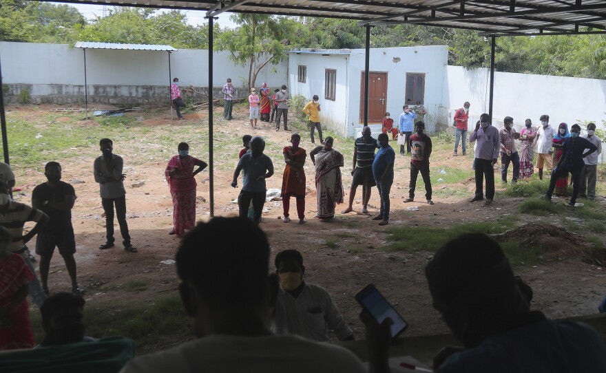 People wait in a queue to register their names before giving their nasal swab samples to test for COVID-19 at a government health center in Hyderabad, India on Saturday. India's coronavirus cases have crossed 4 million.