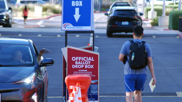 A woman drops her ballot into the drop box as a man walks up to it in Kearny Mesa on June 2, 2026.