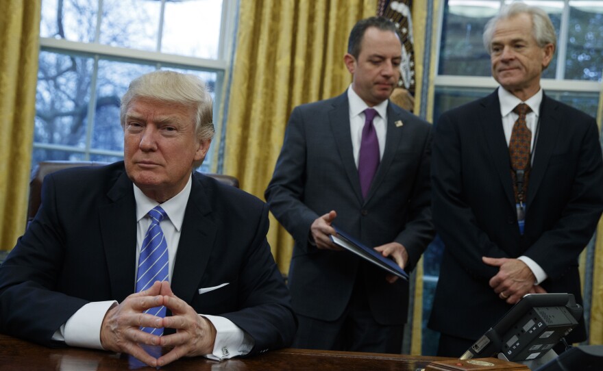 National Trade Council head Peter Navarro (right) and White House Chief of Staff Reince Priebus (center) await President Trump's signing executive orders at the White House on Jan. 23.