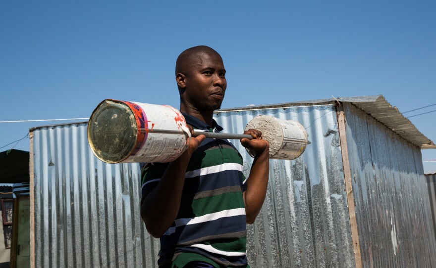 Alfred Sonandi plays around with a makeshift barbell — concrete poured into two tins on either end of a stick. People in the settlement of Covid don't usually wear masks: Living in such close quarters, they may (incorrectly) feel there's no point. They do mask up in public places where masking is mandatory.