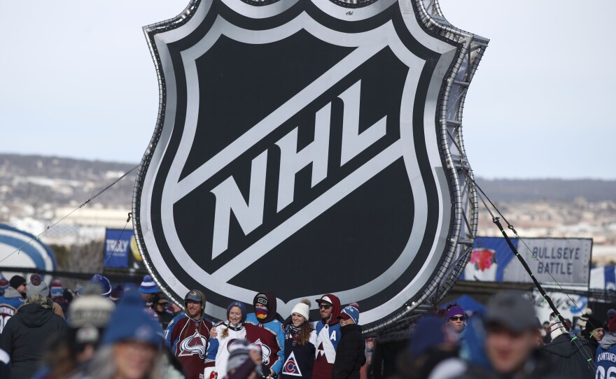 Fans pose below the NHL logo outside Falcon Stadium at the Air Force Academy in Colorado Springs, Colo., in February 2020.