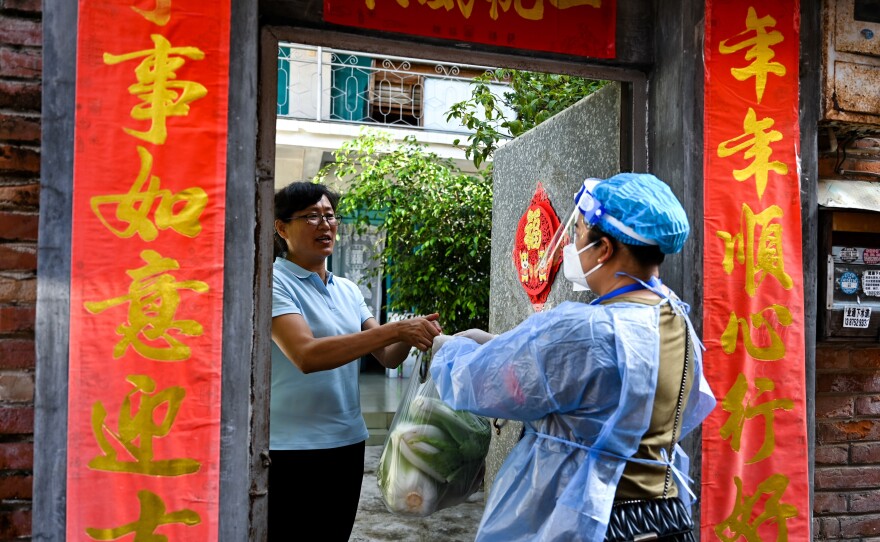 A community worker delivered daily necessities to a household in Ruili City in China's Yunnan Province during a July lockdown triggered by COVID cases. Ruili closed off its city proper and asked all residents to quarantine at home. Classes were suspended. Most establishments were closed with the exception of markets, hospitals and pharmacies. Restaurants could only offer takeout food.