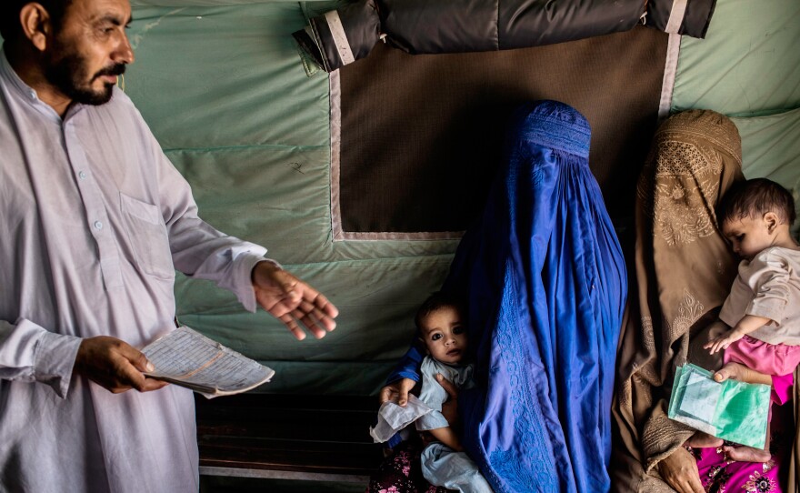 Usman (right), 7 months, and Abdullah (left), 18 months, are held by their mothers while they wait to receive the polio vaccine at the Jalozai refugee camp near Peshawar, Pakistan.