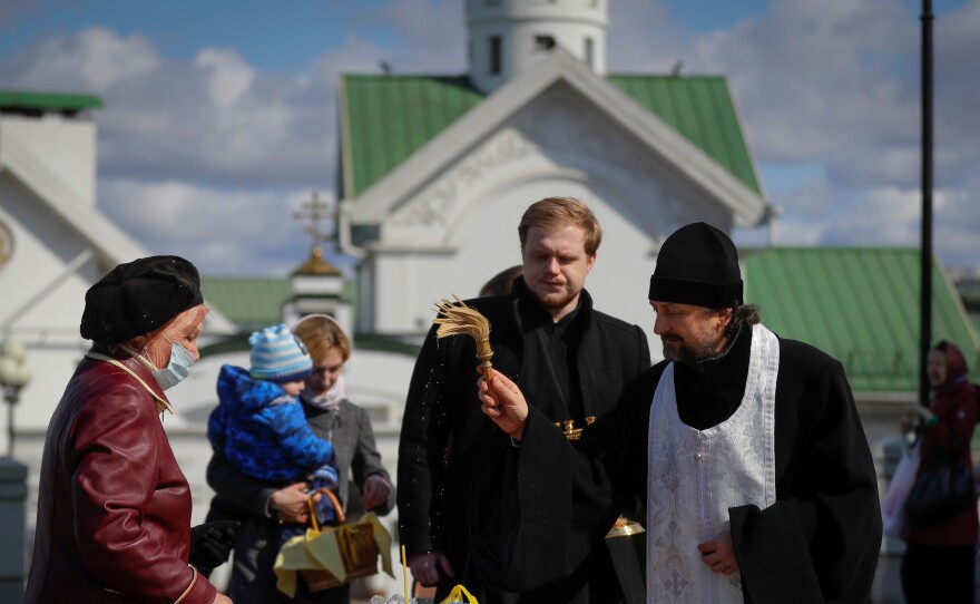 An Orthodox priest blesses traditional Easter cakes and painted eggs in preparation for Easter, outside a church in Minsk, Belarus on Saturday.