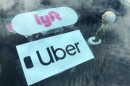Lyft and Uber stickers and a bobblehead figurine are visible on the dashboard of a car, Nov. 5, 2020.