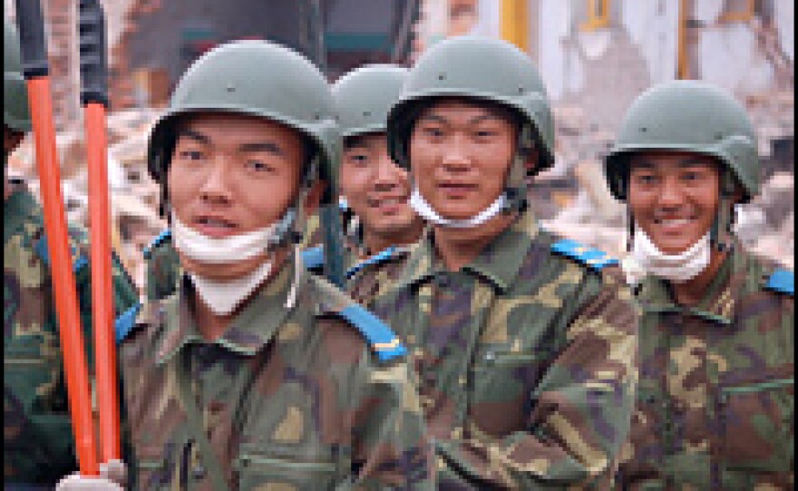 After freeing a man who had been trapped since Monday's quake, soldiers march off proudly.