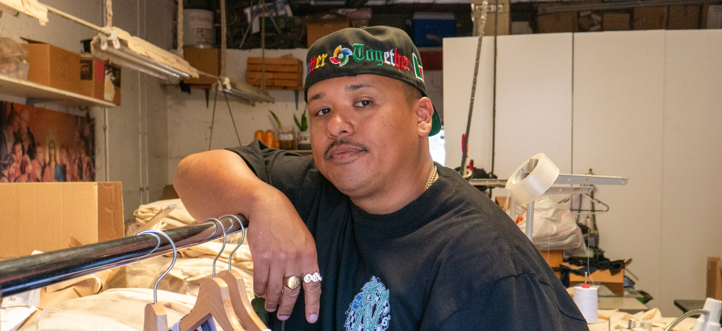 Moss Randy Ortega leans against a clothing rack for a portrait at Norma's Apparel in National City on Aug. 3, 2026.