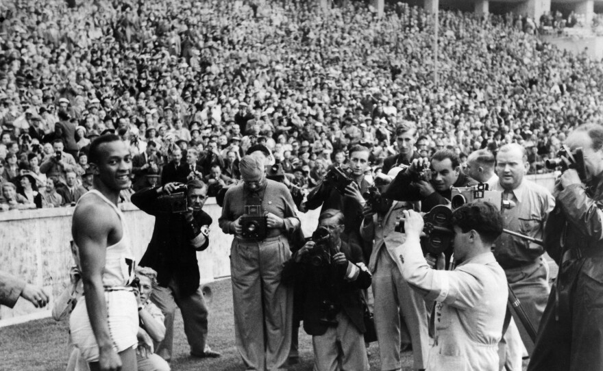 (GERMANY OUT) Jesse Owens (James Cleveland Owens), US-American track and field athlete, won 4 gold medals at the Summer Olympics in Berlin in 1936, Summer Olympics in Berlin in August 1936: Owens is surrounded by press photographers after winning the 100m sprint, among them is Heinrich von der Becke (c, kneeling)