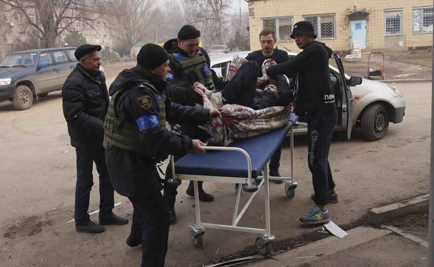 Ukrainian servicemen and volunteers carry a man injured during a shelling attack into hospital number 3 in Mariupol, Ukraine on Tuesday.