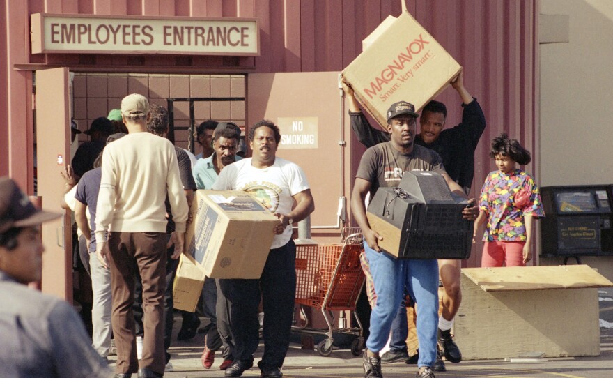 Looters carry televisions out of a Fedco Department Store at La Cienega Boulevard and Rodeo in Los Angeles on May 1, 1992, during the second day of rioting in the city.