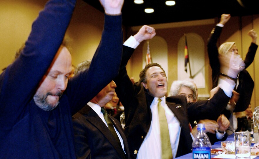 Billy Crystal (from left), New York City Mayor Michael Bloomberg, and Dan Doctoroff, New York City deputy mayor of economic development, cheer after the United States Olympic Committee announced in November 2002 that New York City would represent the U.S. in a bid to host the 2012 Summer Olympics.