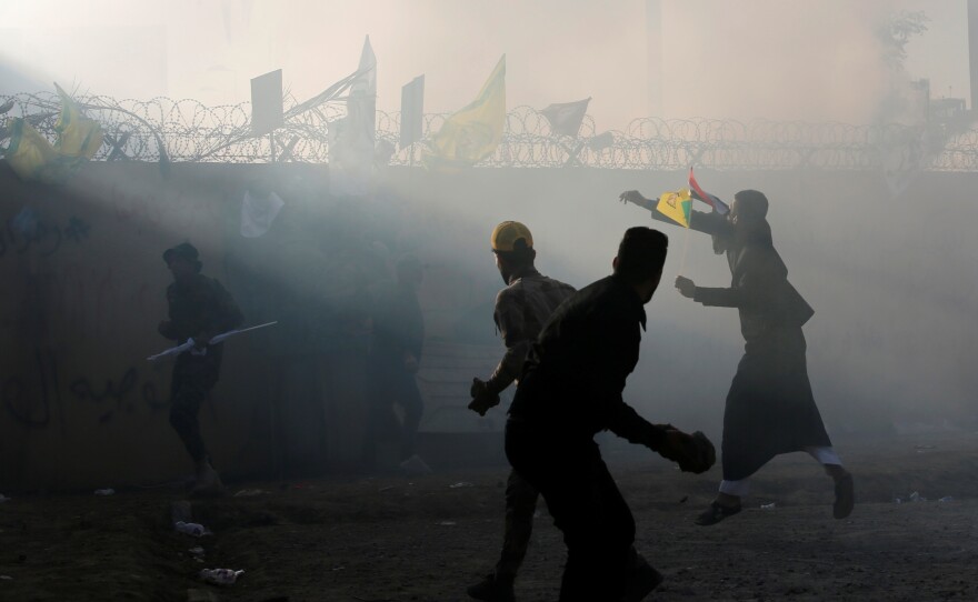 Protesters and militia members throw stones toward the U.S. Embassy in Baghdad on Tuesday.