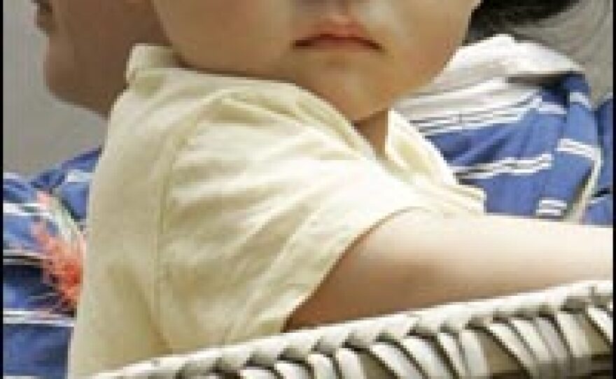 A baby is carried in a basket on his mother's back on a street in Beijing.