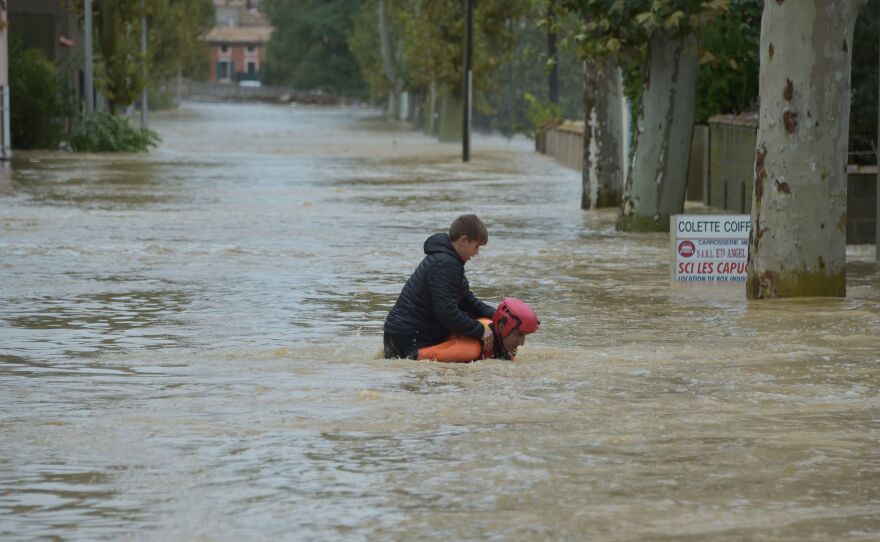 A firefighter helps a youngster reach safety in a flooded street during a rescue operation following heavy rains that saw rivers bursting their banks in Trèbes, near Carcassonne, in southern France.