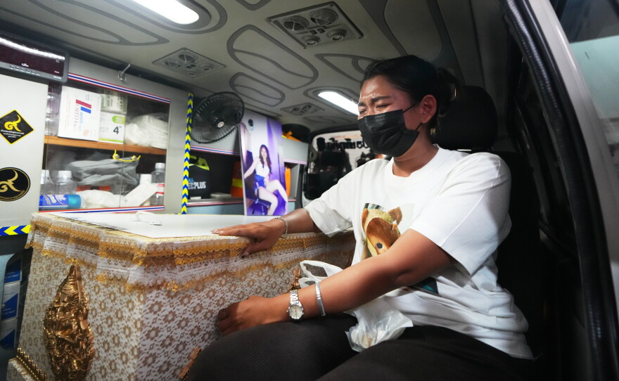 A relative of a victim in a music bar fire sits near the coffin containing the victim's body inside a vehicle as it is transferred from a police hospital in Bangkok, Thailand, Wednesday, July 15, 2026.