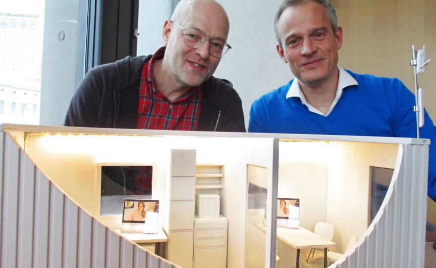 Harald Neidhardt (left) and Mirko Bass, shown here with a model of their mobile medical clinic, had been volunteering to help asylum seekers in Hamburg but wanted to do more. The clinic they created from a refurbished shipping container received more than 3,000 patients between November and the end of April.