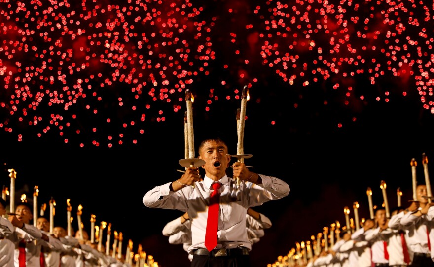 Fireworks explode over participants during a torchlight procession during the celebration marking the 70th anniversary of North Korea's foundation in Pyongyang, North Korea, on Sept. 10, 2018.