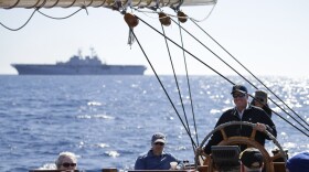 Troy Sears steers the yacht America as the USS America sits on the horizon during a whale watching trip off the coast of San Diego, March 5, 2015.