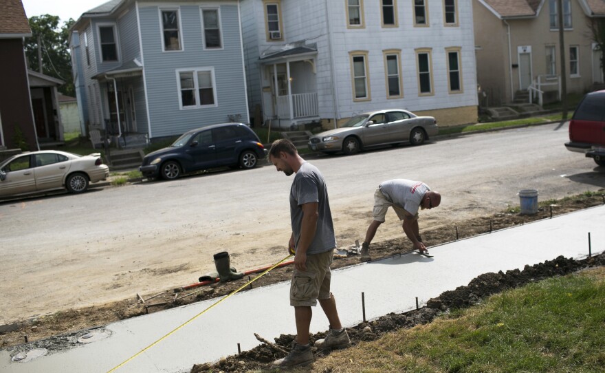 People work on restoring a sidewalk in Springfield. The loss of so many jobs has caused the city's population to drop from more than 80,000 in the 1970s to fewer than 60,000 today.