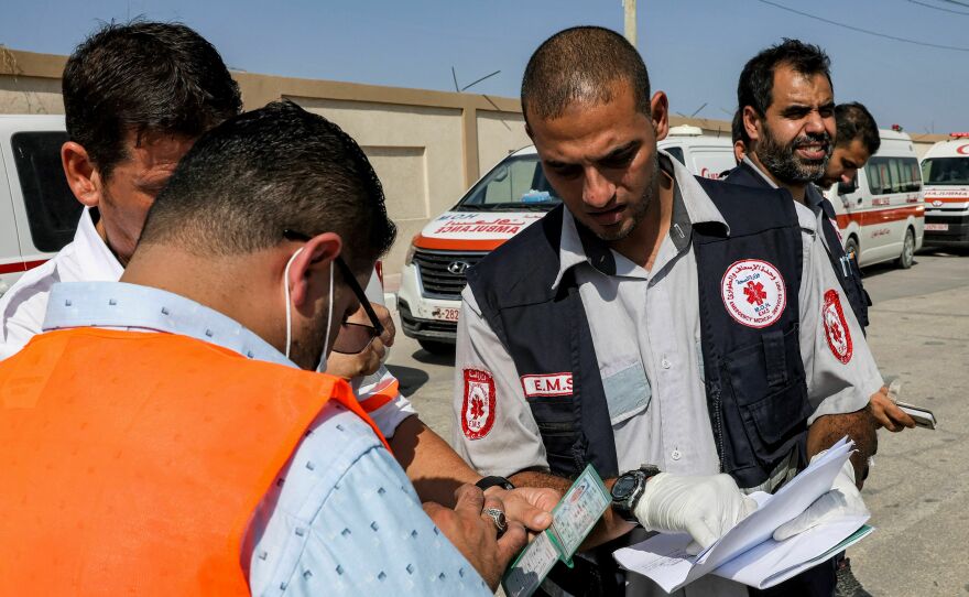 Palestinian health ministry paramedics check the travel documents of a person waiting to cross to Egypt at the Rafah border crossing in the southern Gaza Strip on Wednesday.