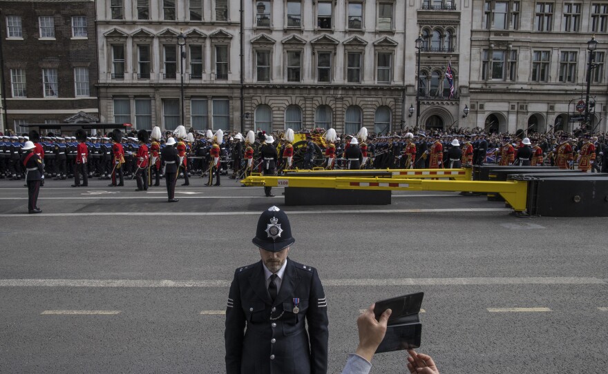 A spectator photographs the coffin of Queen Elizabeth II during the funeral procession for the late monarch as mourners gather to say goodbye outside the Palace of Westminster and the houses of parliament in London on Monday.