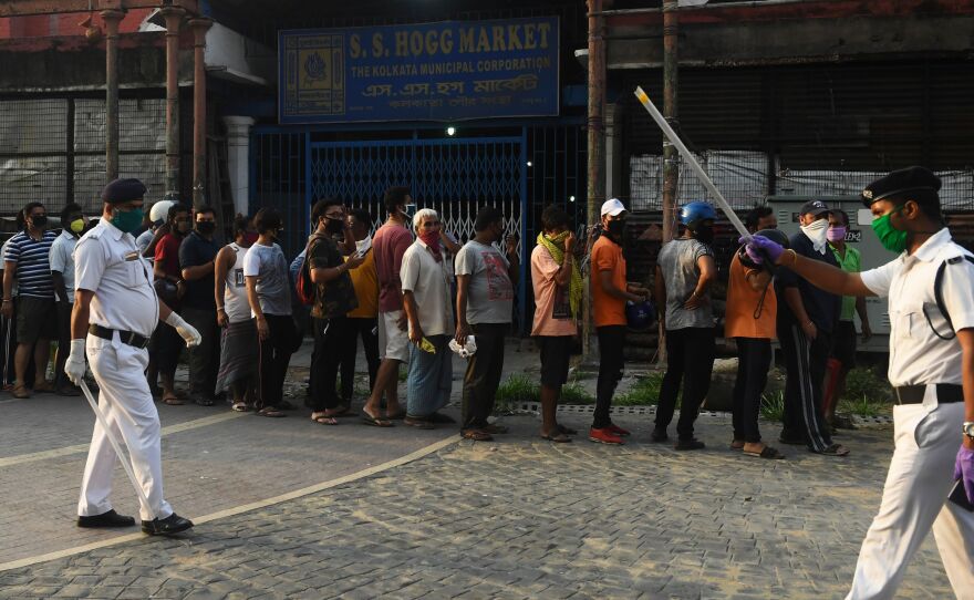 Police officials patrol as people stand in line to buy alcohol in Kolkata on Monday.