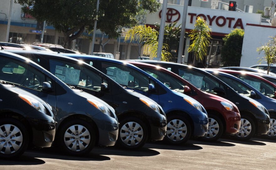 Cars are lined up in a row at a Toyota dealership.