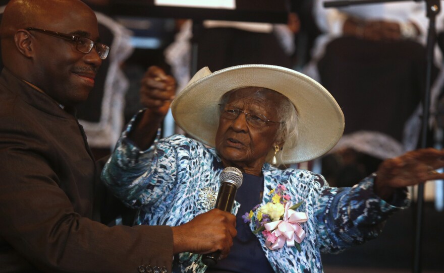 Jeralean Talley addresses the congregation as her pastor, Reverend Dana Darby, holds the microphone for her during a celebration of her 115th birthday.