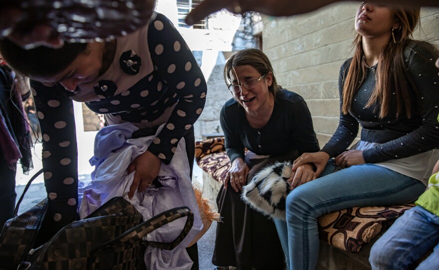 Khairya Murad (right), the sister of Nobel Peace laureate Nadia Murad, and other women from Kocho are overcome with emotion at the Yazidi temple in Lalish. They have brought clothing to be blessed and sprinkled with sacred spring water as part of the burial rites for their family members once the remains are exhumed from mass graves and identified through DNA tests.