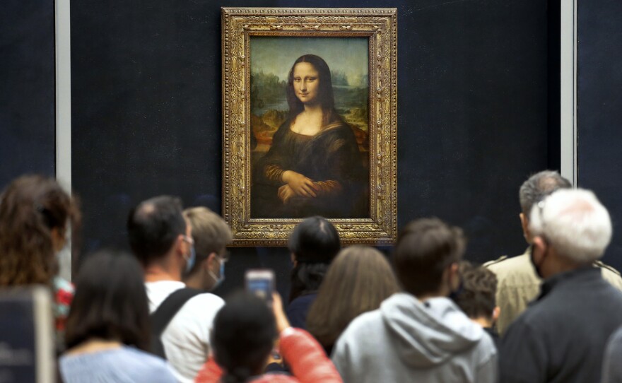 Visitors wearing face masks wait to see the Mona Lisa at the Louvre Museum on Monday. The most visited museum in the world reopened to the public after closing in March.