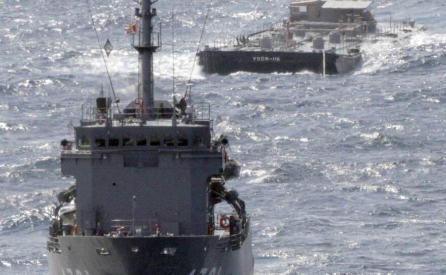 A U.S. Navy barge, back, is towed Saturday by a Japanese Maritime Self-Defense Force support ship off the coast of Japan. The barge is carrying 275,000 gallons of freshwater to support cooling efforts at the damaged Fukushima Dai-ichi nuclear power plant.