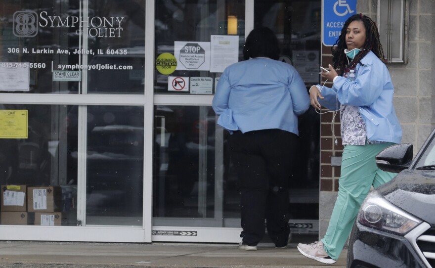 Employees of the Symphony of Joliet nursing home in Joliet, Ill., go to work last Friday. At least 21 people, including two staff members, have died of COVID-19 at the facility.