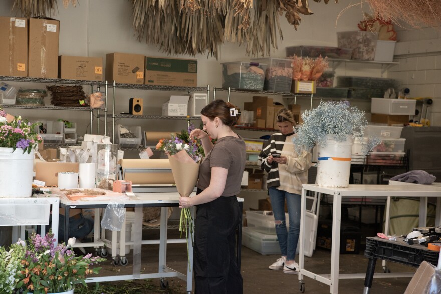 Native Poppy co-owner Natalie Gill is shown in the background and a worker putting together a floral arrangement is shown in the foreground of Native Poppy on March 21, 2024.